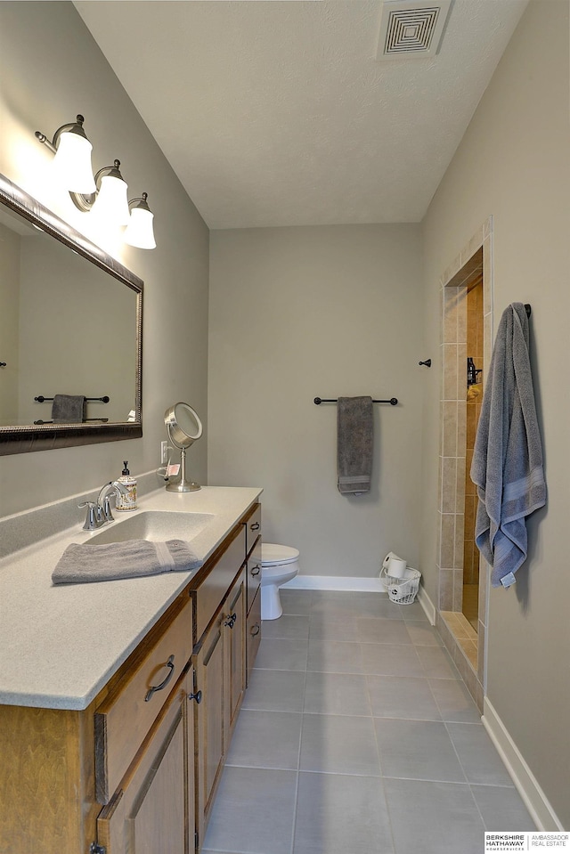 bathroom featuring baseboards, visible vents, tiled shower, tile patterned flooring, and toilet