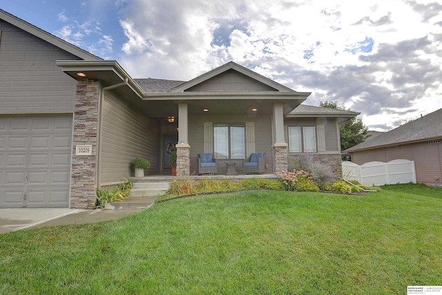 view of front of house with a front yard, fence, covered porch, and stone siding