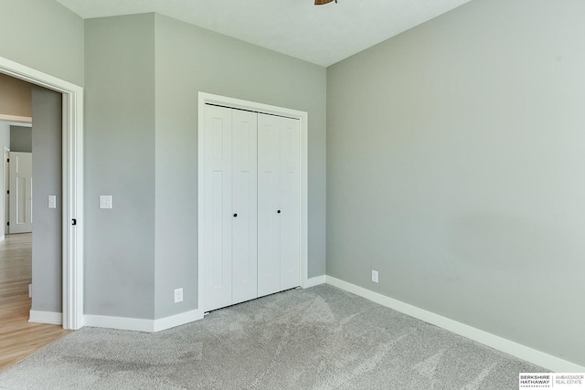 unfurnished bedroom with light colored carpet and a closet