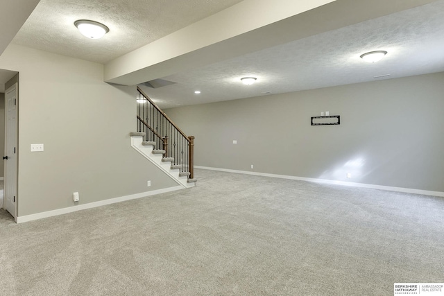 finished basement with baseboards, a textured ceiling, light carpet, and stairs