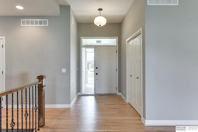 foyer entrance featuring visible vents, light wood-type flooring, and baseboards