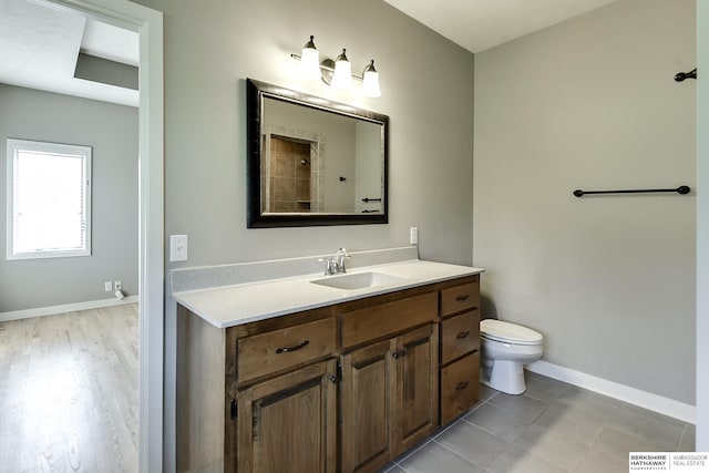 bathroom with baseboards, toilet, and vanity