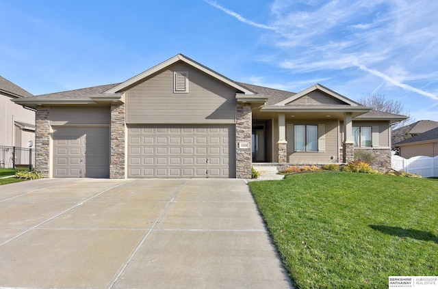 view of front of property featuring a front yard, fence, an attached garage, concrete driveway, and stone siding