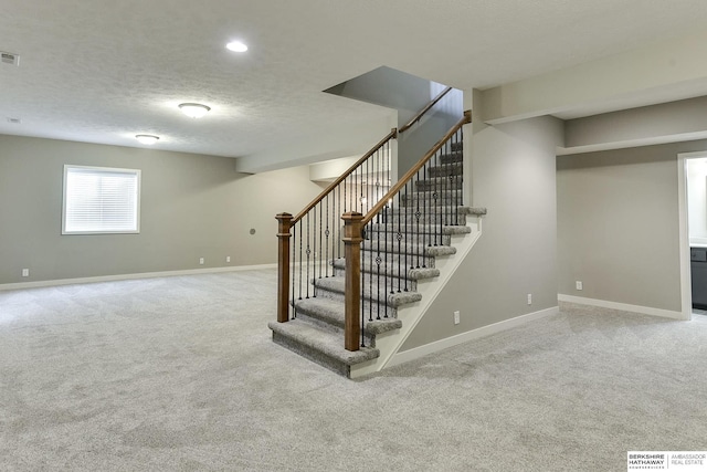 basement with a textured ceiling and light colored carpet