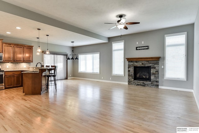 kitchen featuring brown cabinetry, electric range, light wood-style floors, a kitchen breakfast bar, and open floor plan