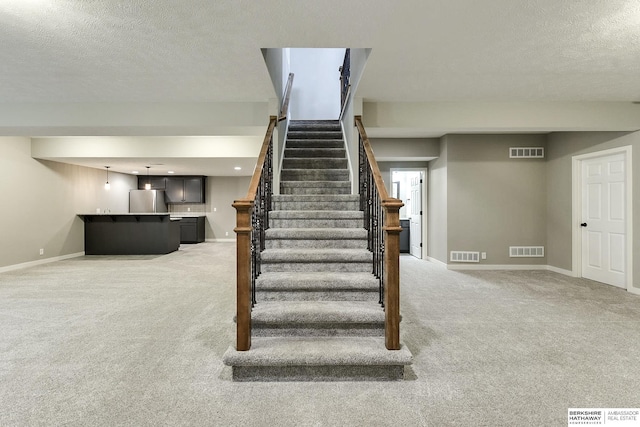 staircase with carpet and a textured ceiling