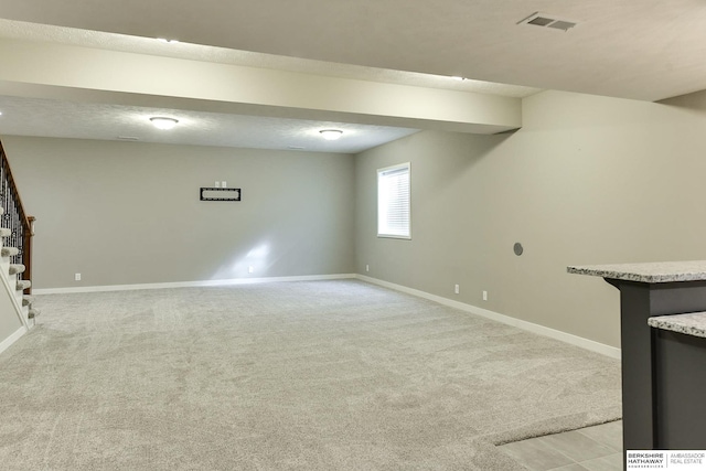 basement featuring stairs, light colored carpet, visible vents, and baseboards