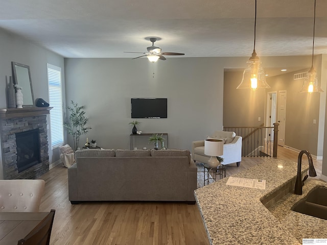 living room with visible vents, a fireplace, light wood-type flooring, and baseboards