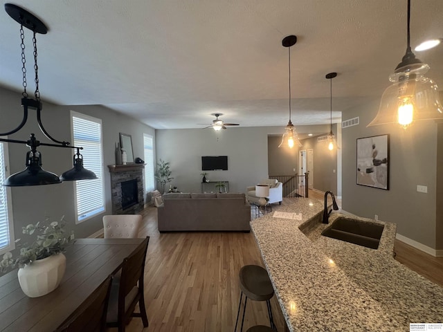 living area featuring visible vents, baseboards, a fireplace, wood finished floors, and a ceiling fan