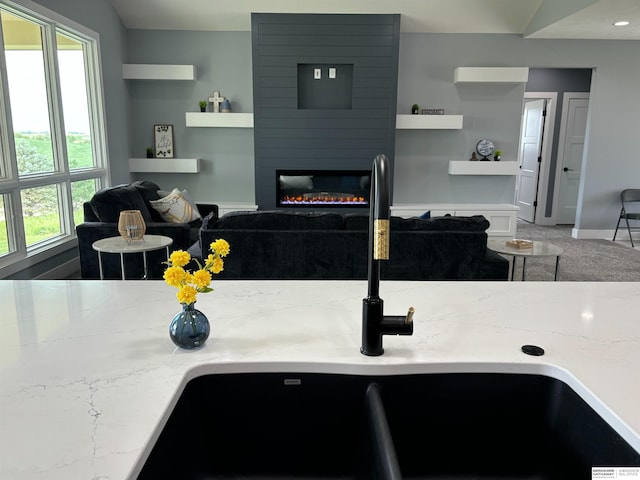 kitchen with light stone counters, sink, and a large fireplace