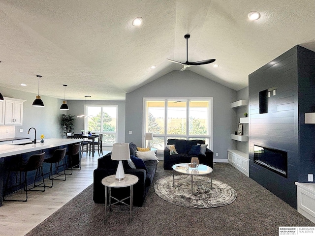 living room featuring sink, light hardwood / wood-style flooring, ceiling fan, built in features, and a textured ceiling