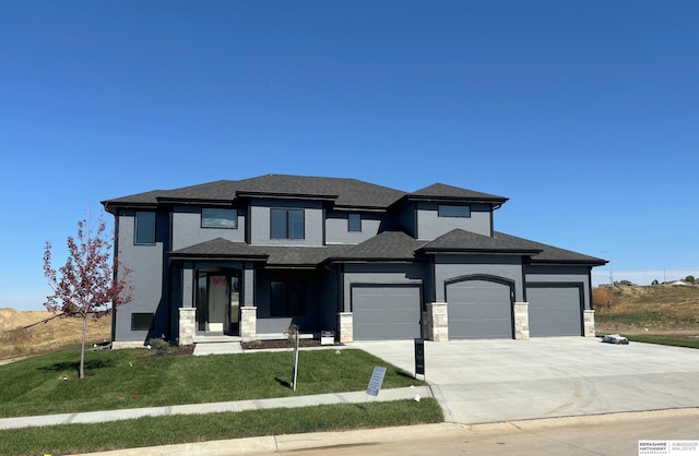 prairie-style house with a garage and a front lawn