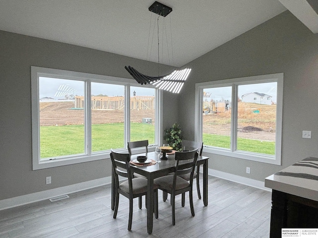 dining room featuring lofted ceiling and light hardwood / wood-style flooring