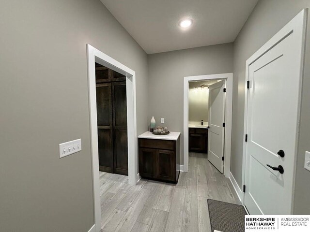 hallway with sink and light hardwood / wood-style flooring