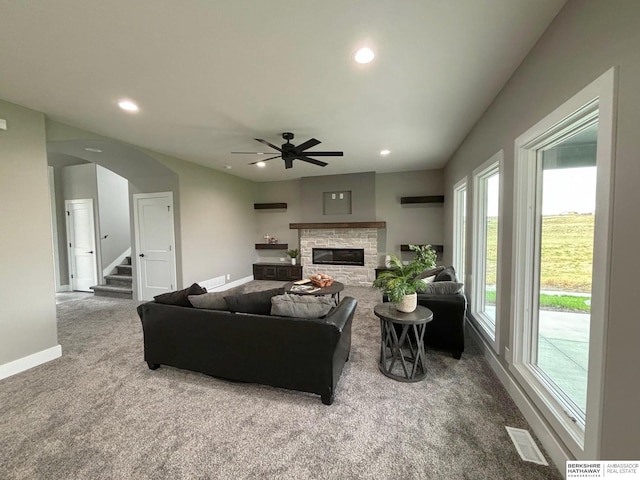 carpeted living room featuring ceiling fan and a fireplace