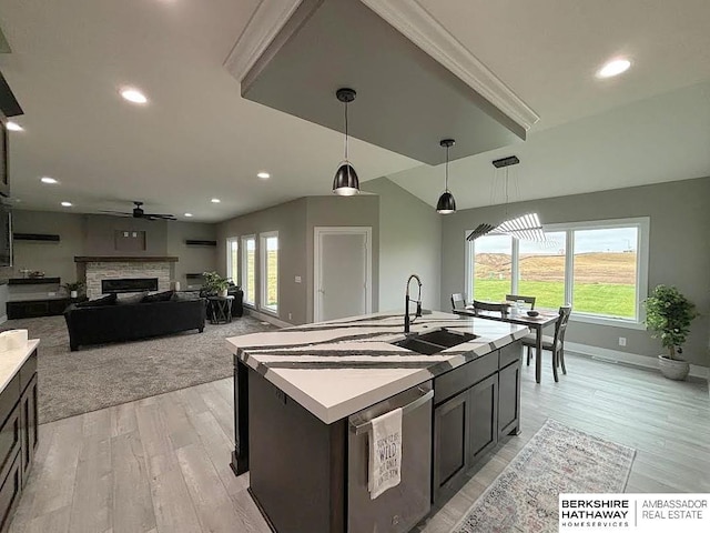 kitchen featuring pendant lighting, sink, an island with sink, stainless steel dishwasher, and light wood-type flooring