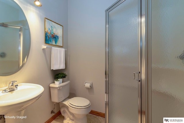 bathroom featuring toilet, a shower with shower door, and sink