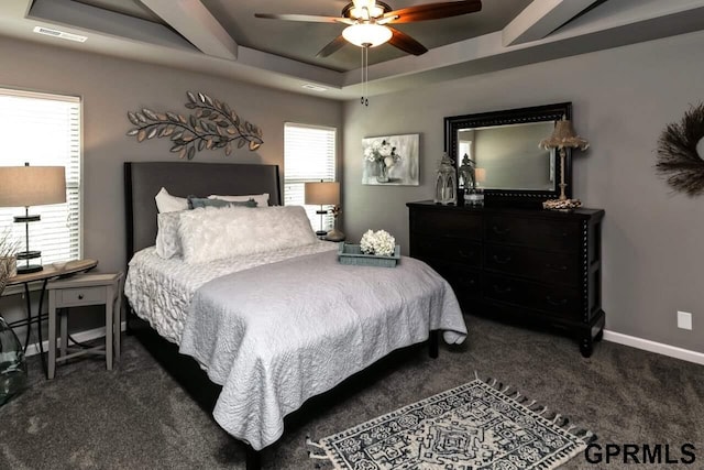 carpeted bedroom featuring a tray ceiling and ceiling fan