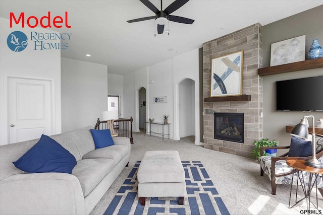 living room featuring ceiling fan, a tiled fireplace, and carpet floors