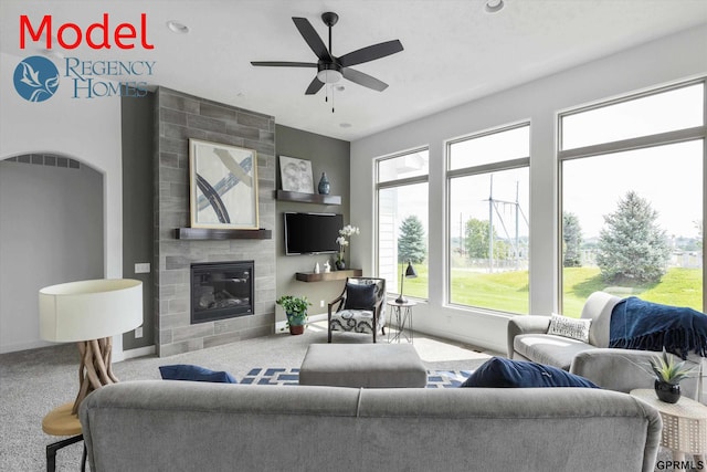 carpeted living room with a tile fireplace and ceiling fan