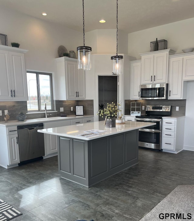 kitchen with stainless steel appliances, a center island, pendant lighting, decorative backsplash, and white cabinetry