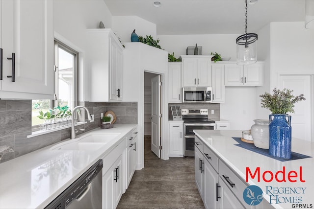 kitchen featuring sink, stainless steel appliances, white cabinetry, and decorative light fixtures