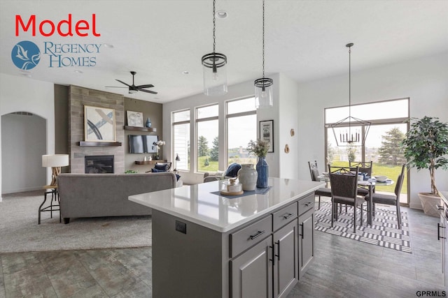 kitchen with decorative light fixtures, a fireplace, ceiling fan with notable chandelier, a kitchen island, and gray cabinetry