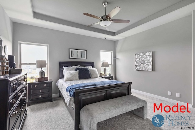 carpeted bedroom featuring ceiling fan and a tray ceiling