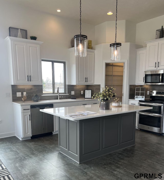 kitchen with white cabinets, appliances with stainless steel finishes, and hanging light fixtures