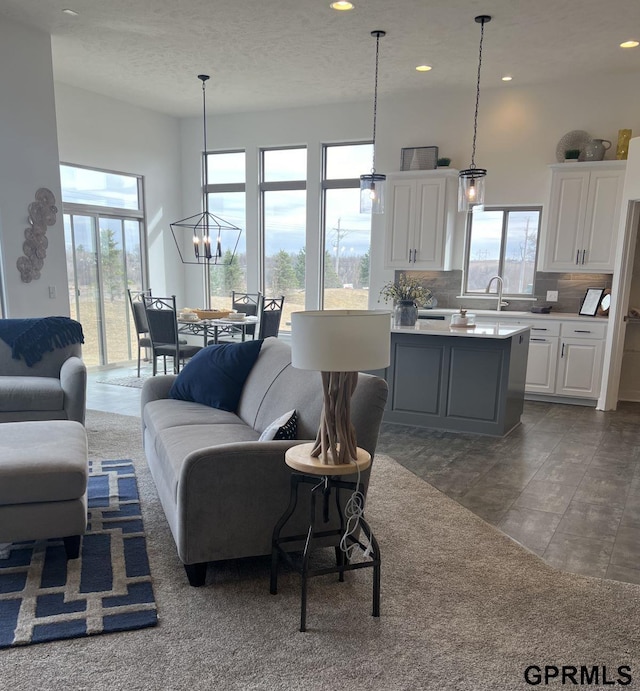 living room with sink, a high ceiling, an inviting chandelier, and a healthy amount of sunlight