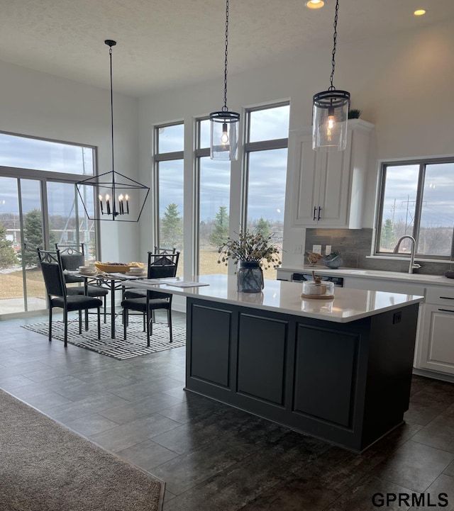 kitchen with decorative light fixtures, white cabinetry, an inviting chandelier, a center island, and tasteful backsplash