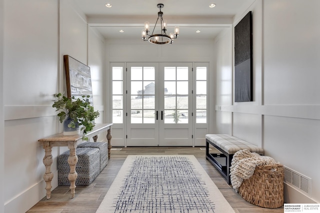 doorway to outside featuring wood-type flooring and a notable chandelier