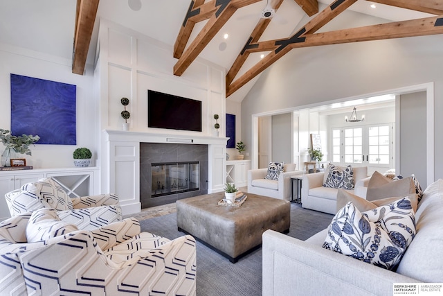 living room featuring beamed ceiling, high vaulted ceiling, a tile fireplace, and a chandelier