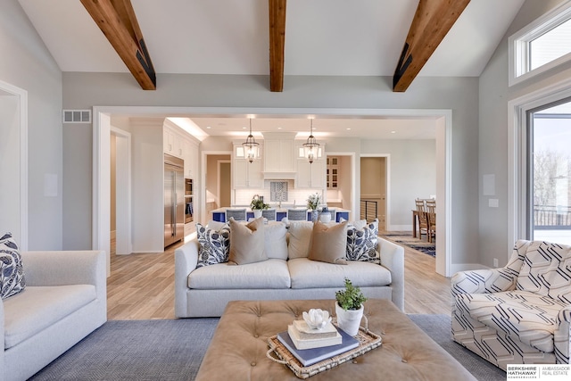 living room featuring vaulted ceiling with beams, light hardwood / wood-style flooring, and an inviting chandelier