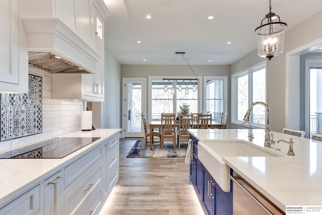 kitchen with custom exhaust hood, sink, blue cabinetry, decorative light fixtures, and white cabinets