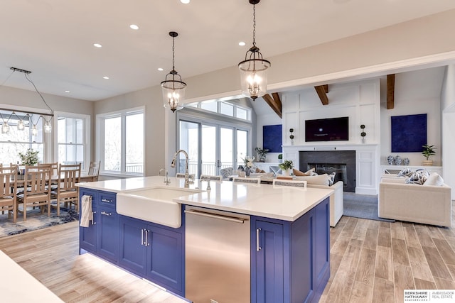 kitchen with blue cabinetry, sink, stainless steel dishwasher, and an inviting chandelier