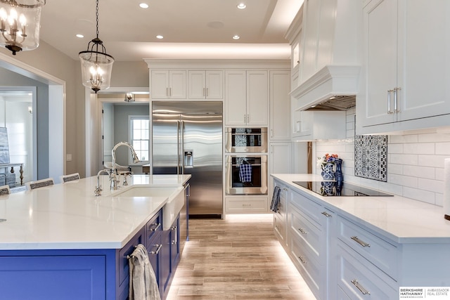 kitchen with pendant lighting, premium range hood, appliances with stainless steel finishes, tasteful backsplash, and white cabinetry