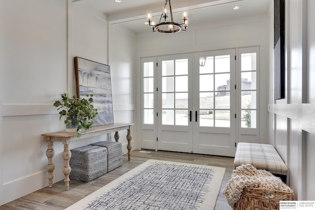 doorway to outside featuring plenty of natural light, light hardwood / wood-style flooring, and a notable chandelier