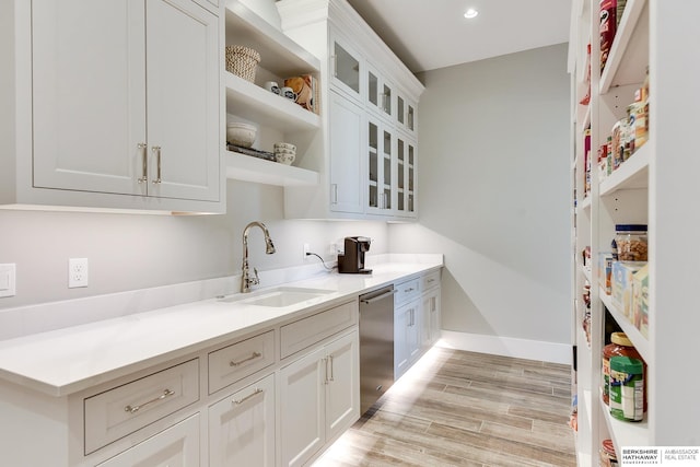 kitchen with sink, white cabinets, stainless steel dishwasher, and light hardwood / wood-style flooring