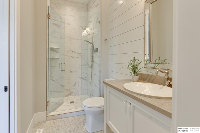 bathroom with wood walls, a shower with door, vanity, and toilet