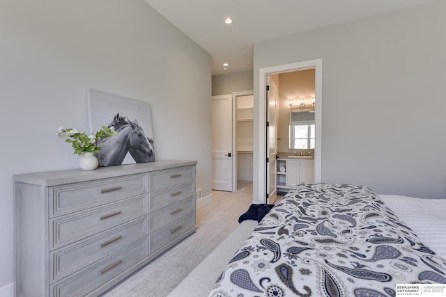 bedroom with ensuite bathroom, a spacious closet, a closet, and sink