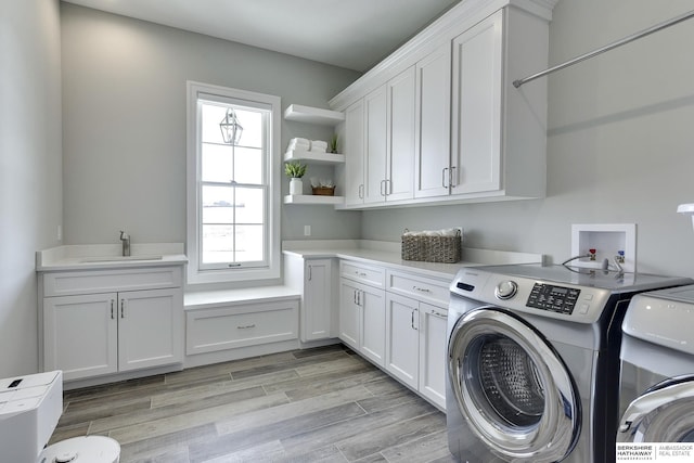 laundry room featuring cabinets, separate washer and dryer, sink, and light wood-type flooring