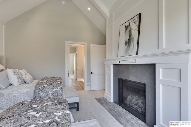 bedroom featuring a tile fireplace and high vaulted ceiling