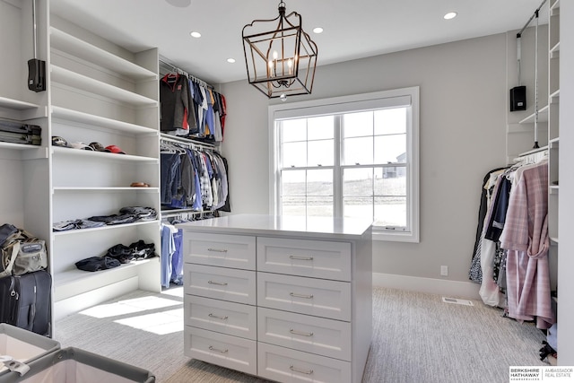 spacious closet featuring light colored carpet and a notable chandelier