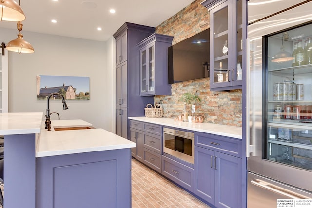 kitchen featuring high end fridge, tasteful backsplash, hanging light fixtures, and sink