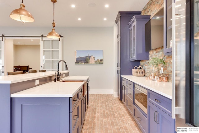 kitchen with a barn door, built in microwave, sink, and hanging light fixtures