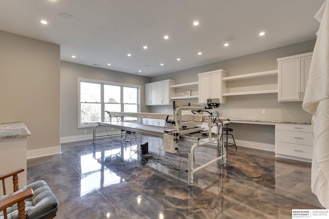 kitchen with white cabinetry, built in desk, and light stone counters