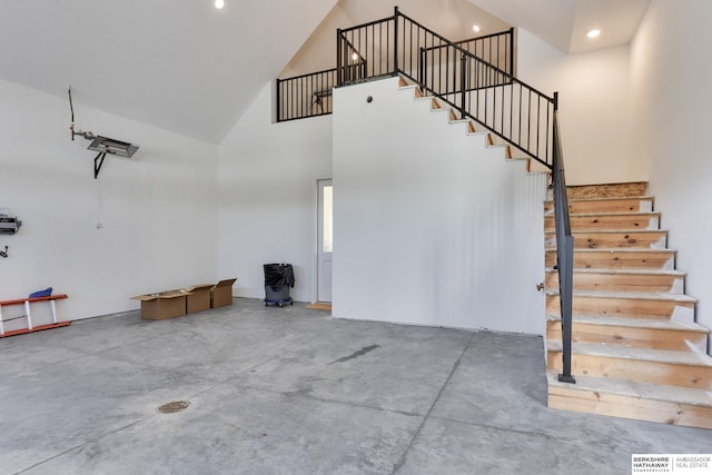 staircase featuring a towering ceiling and concrete flooring