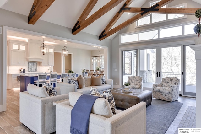 living room with high vaulted ceiling, french doors, sink, a notable chandelier, and beam ceiling