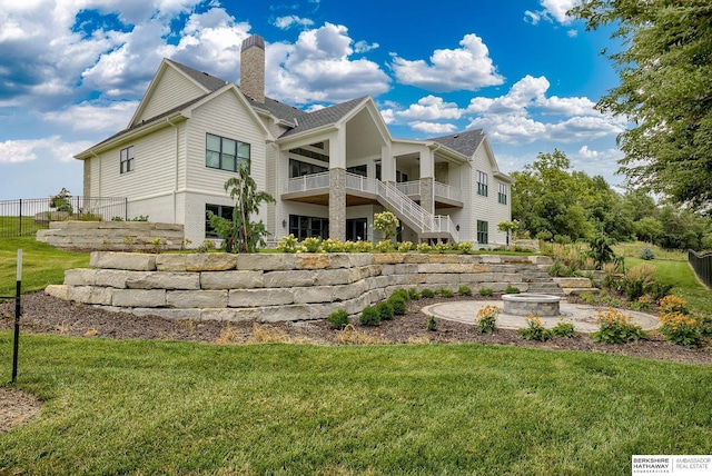 back of house with a yard and a fire pit